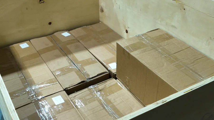 Worker positioning cartons within a wooden export packing crate