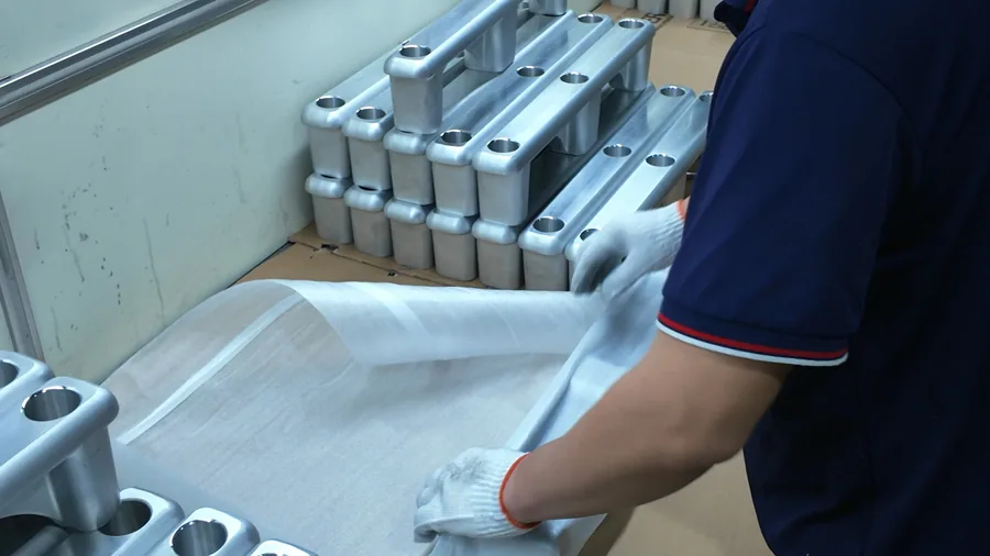 Worker applying protective wrapping to metal support frames at Tianhui